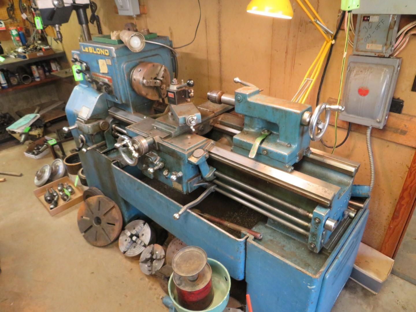 Blue metal lathe with various attachments in a workshop.