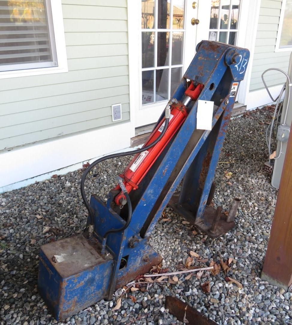 Blue hydraulic post driver on gravel. Red cylinder.