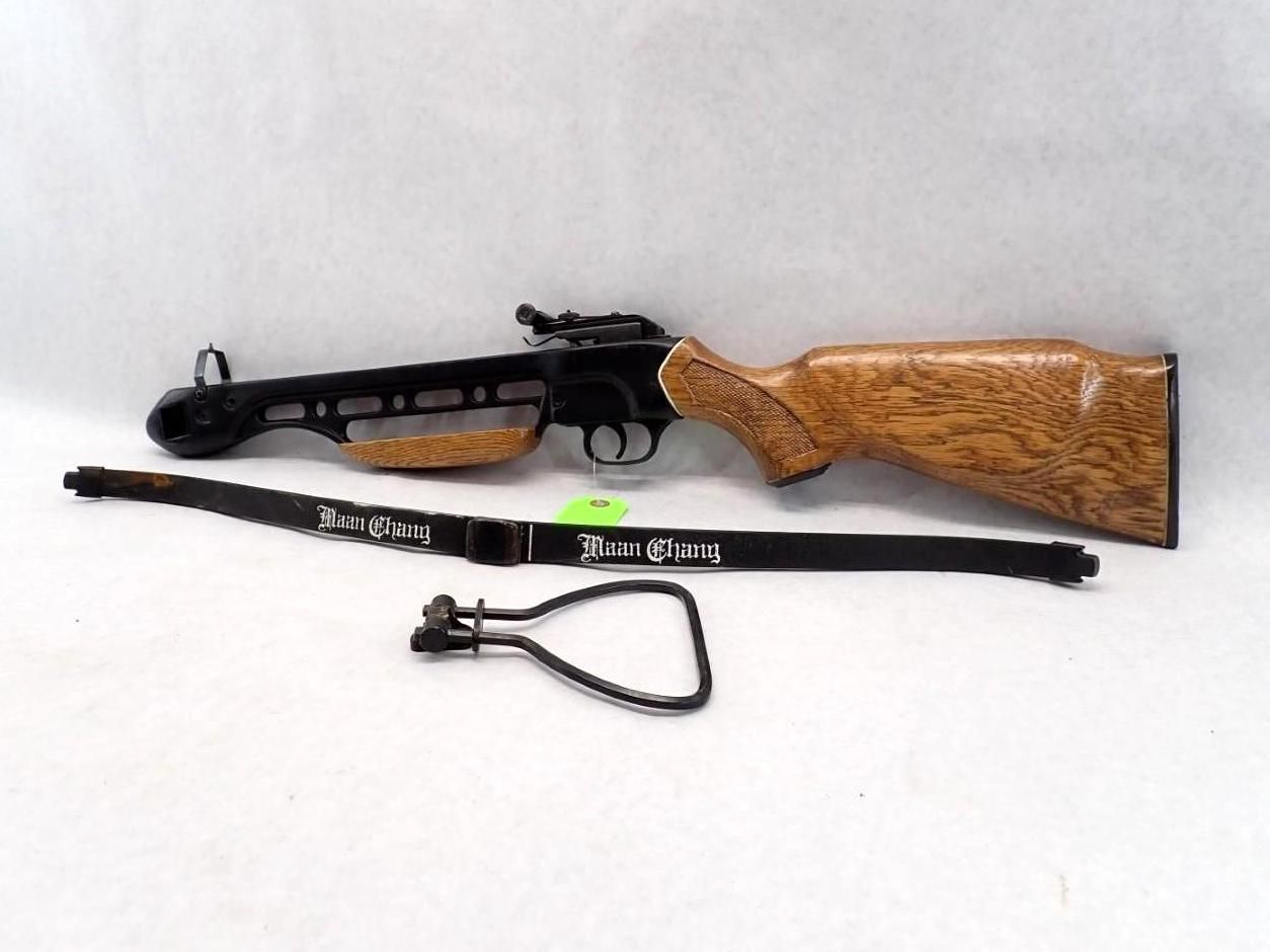 Black and wood-toned crossbow with a black sling against a white backdrop.