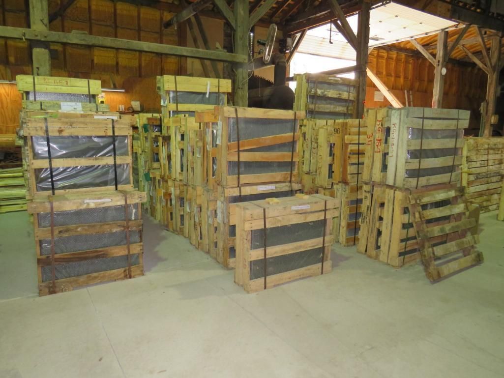 Granite monuments stacked in a warehouse. Some crates are sealed with plastic wrap and straps.
