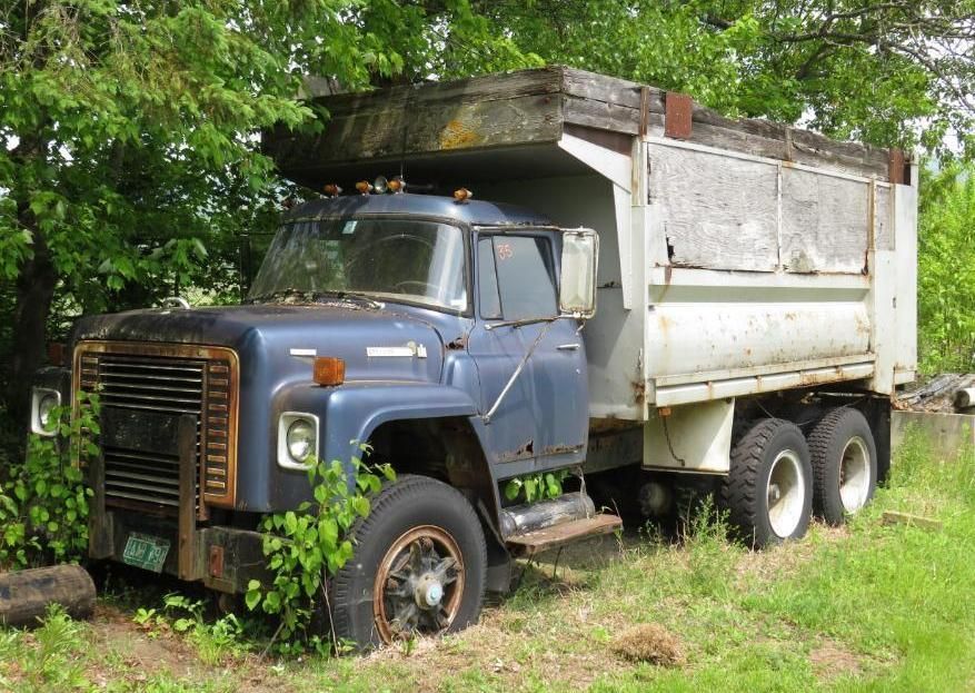 Blue and tan dump truck, parked in grass.