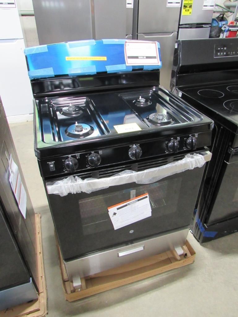 Black gas range appliance on a wooden pallet, in a store.
