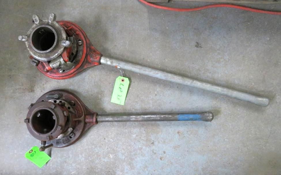 Two pipe threading tools with red bodies, silver handles, and round heads.