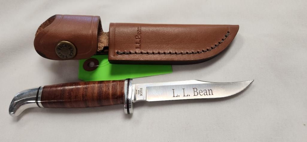 Brown leather-handled knife with sheath on a white surface. The blade is inscribed with