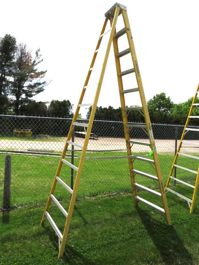 Yellow A-frame ladder set up outdoors on green grass.