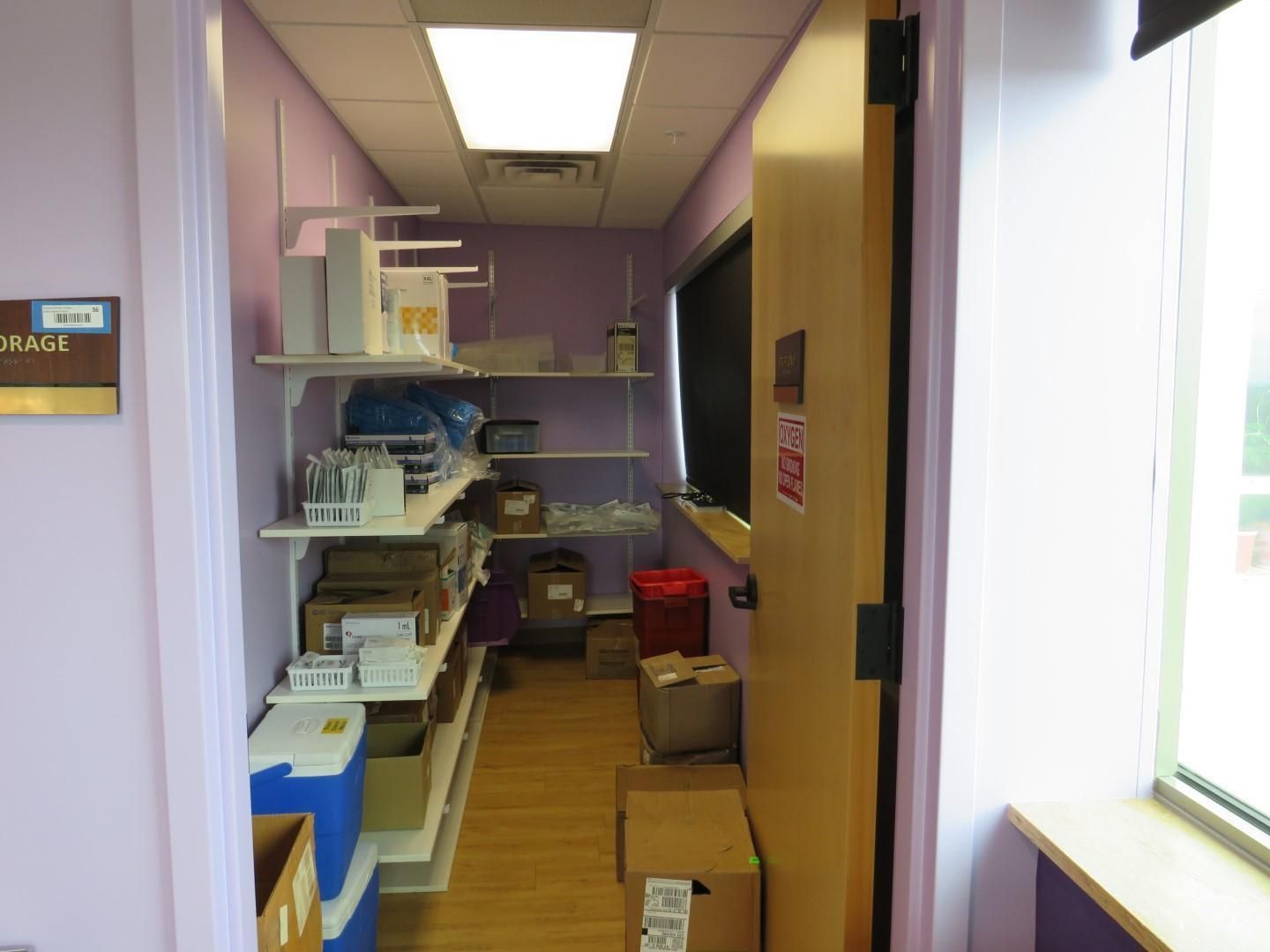 Storage room with shelves, supplies, doorway, and window.