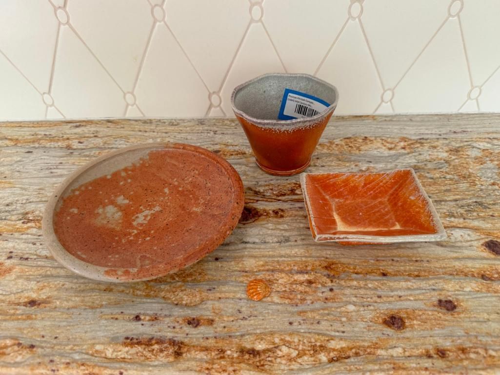 Three ceramic dishes on a rustic countertop: oval, square, and conical, all with reddish-brown contents.