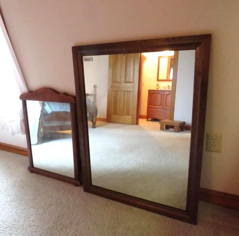 Two wooden-framed mirrors on a carpeted floor.