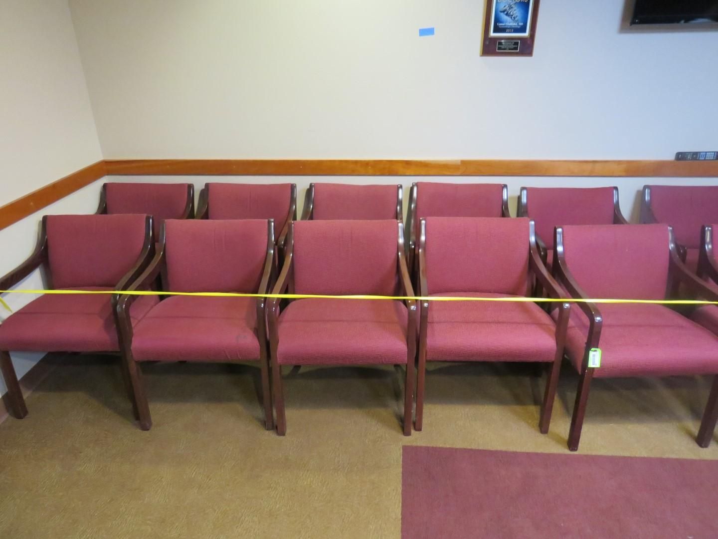 Row of maroon armchairs in a waiting room; yellow tape across the chairs.