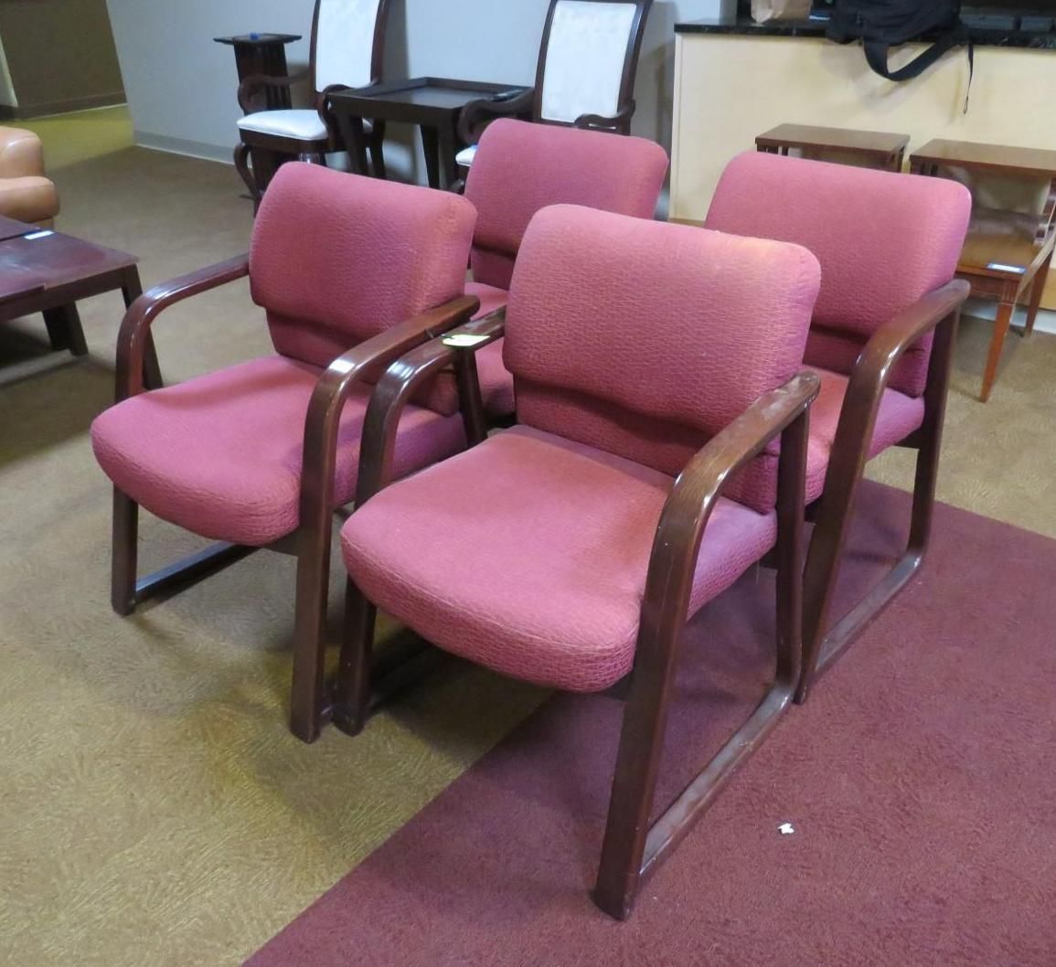 Four pink upholstered armchairs arranged indoors, brown wooden frames.