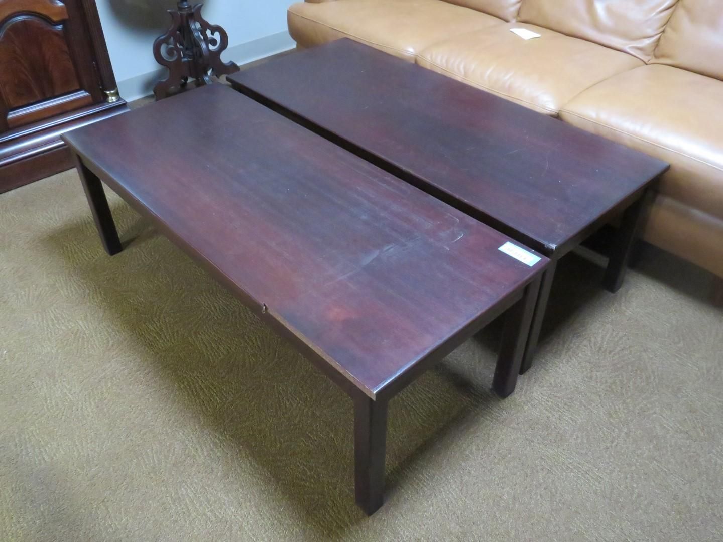 Two rectangular dark wood coffee tables side-by-side on a light brown carpet, next to a tan sofa.