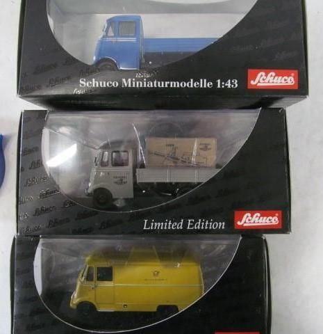 Three Schuco miniature model trucks in boxes: blue, grey with cargo, yellow Post.