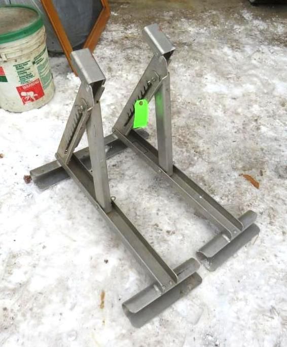 Metal motorcycle stand outdoors on snowy ground.