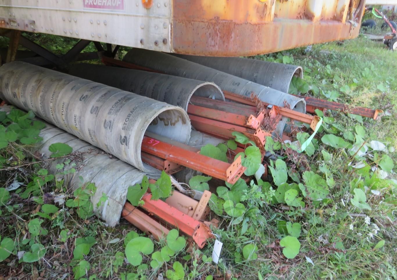Orange metal beams stored inside gray concrete tubes.