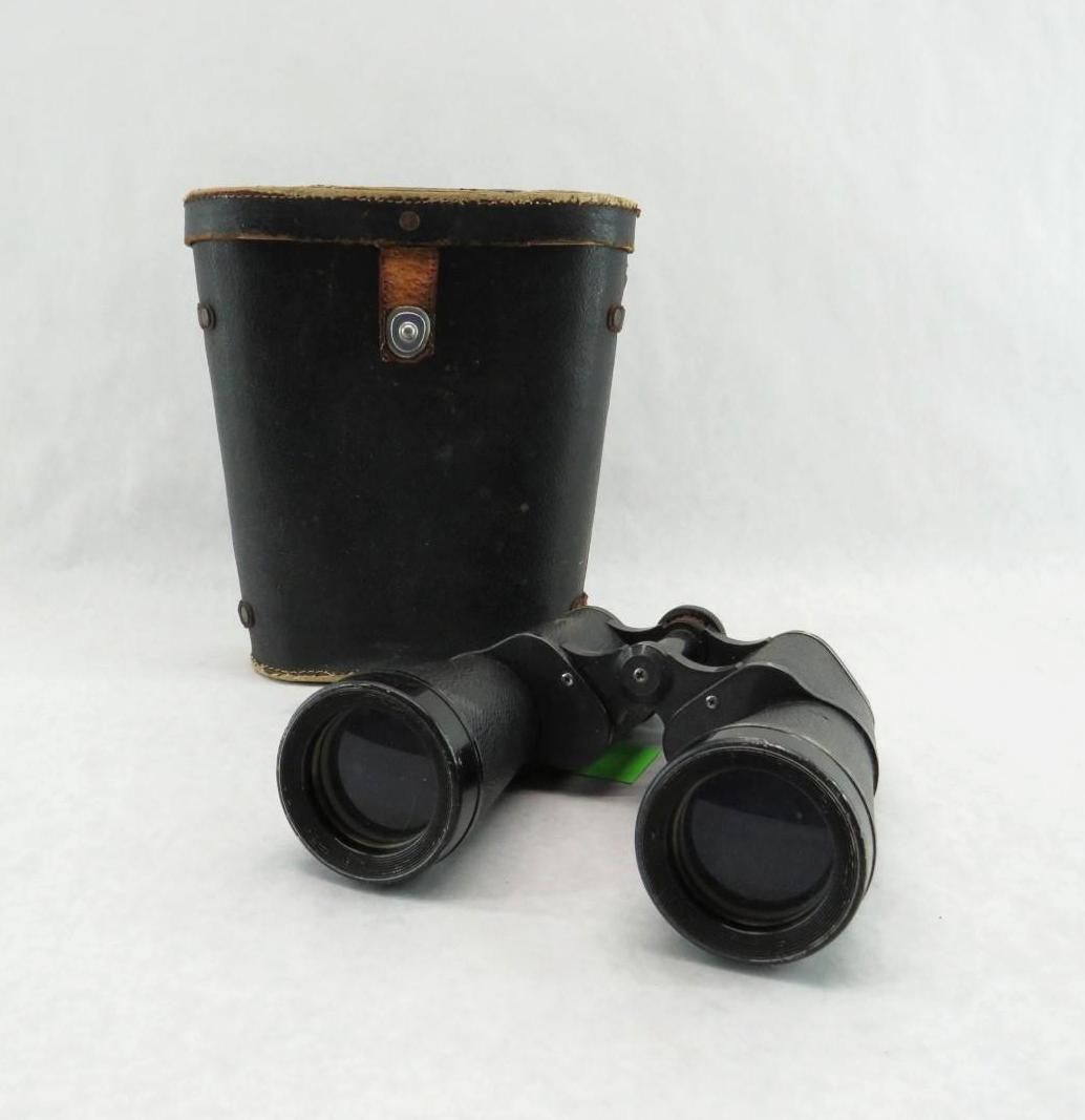 Black binoculars with a black leather case on a white surface.