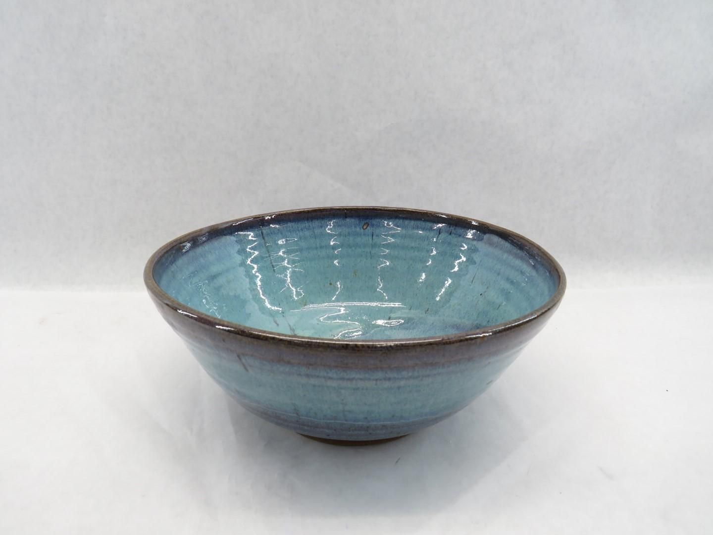 Blue ceramic bowl with a dark brown rim, set against a white background.