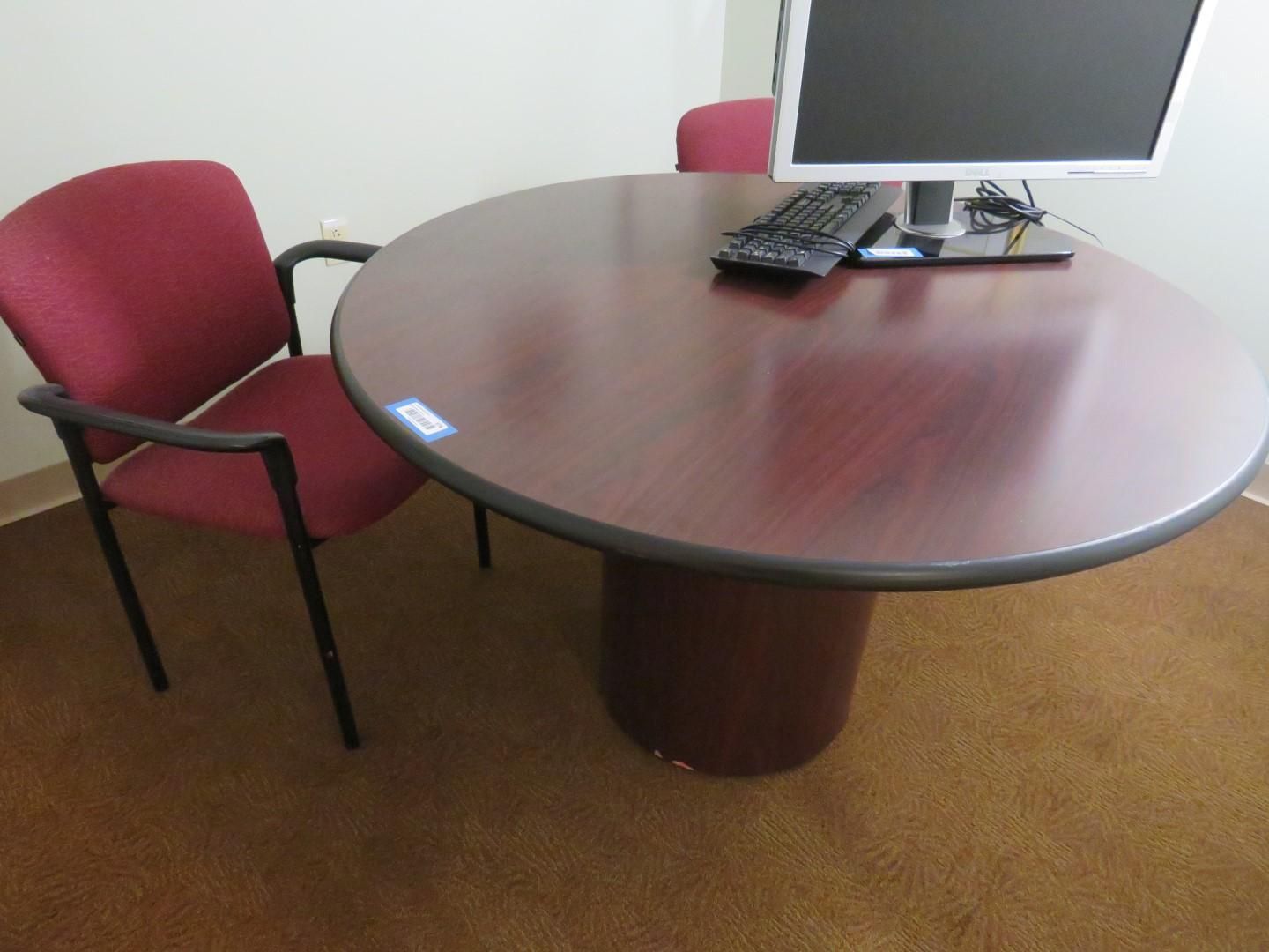 Round wooden table with monitor, keyboard and two maroon chairs on carpet.