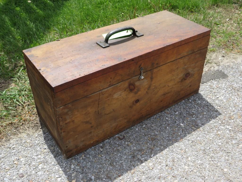 Wooden toolbox with a handle and latch, on concrete.