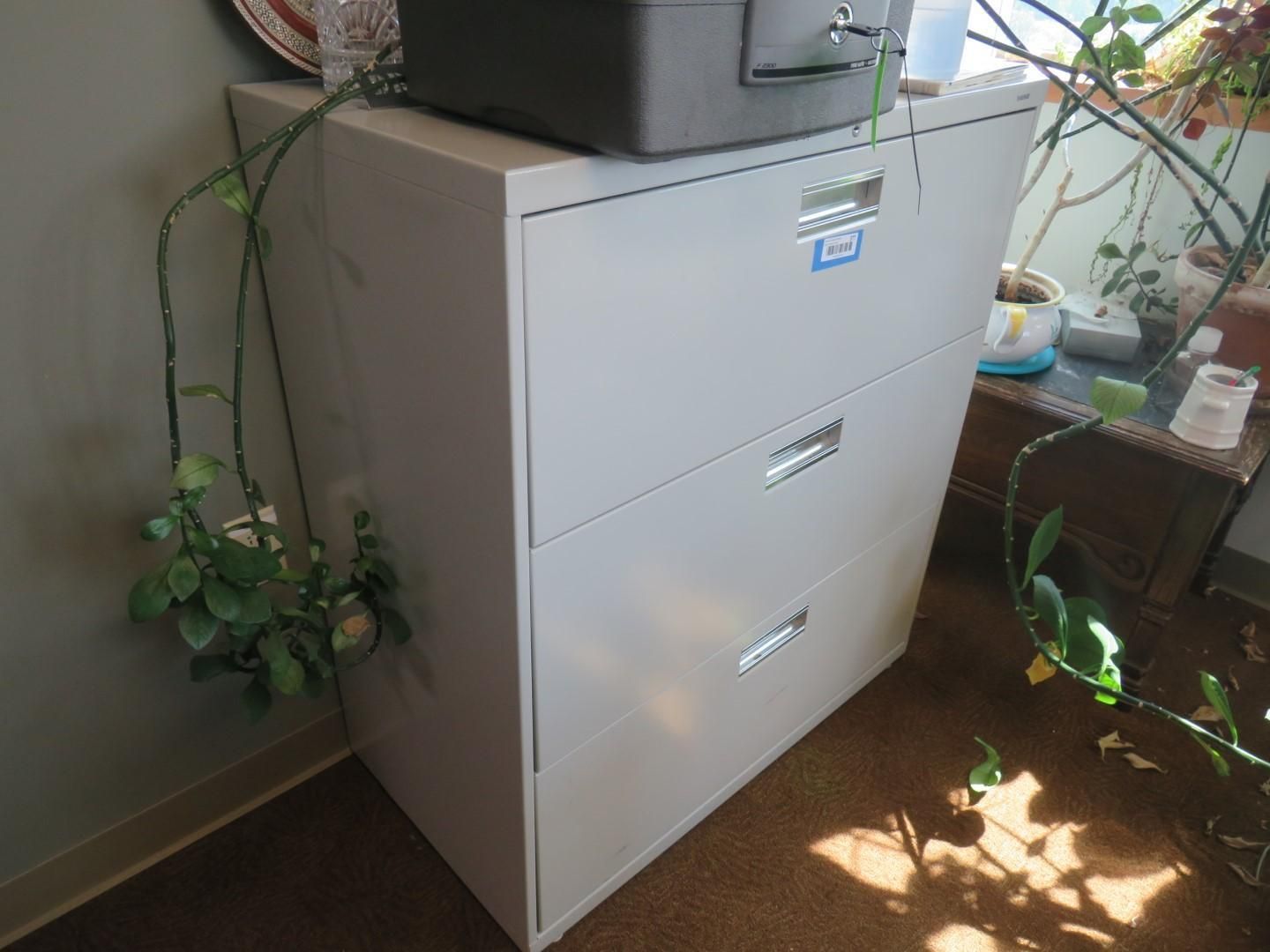 Gray three-drawer filing cabinet in a corner.