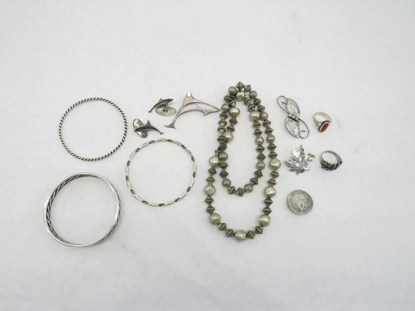 Jewelry on white surface including bracelets, necklaces, rings, and pins.