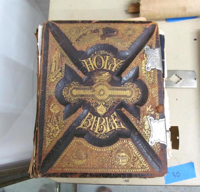 Close-up of an antique Holy Bible with embossed gold and black cover, aged and worn.