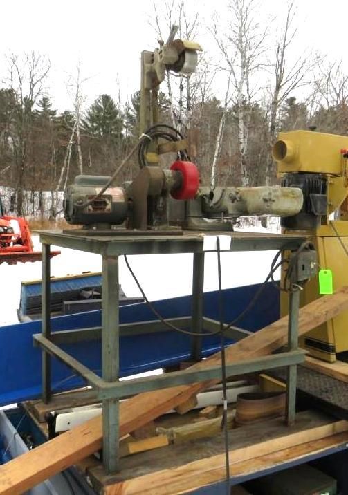 Industrial grinder machine on a metal stand, outdoors with snow in the background.