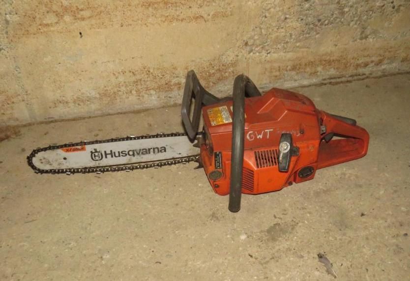 Orange Husqvarna chainsaw on a concrete surface.