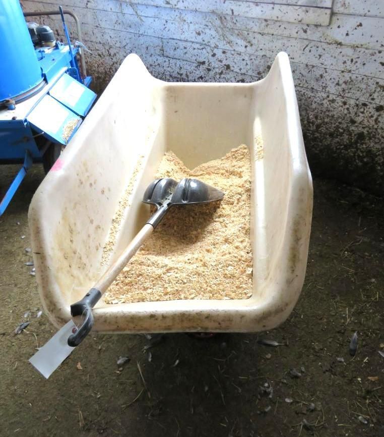 A wheelbarrow filled with wood shavings.