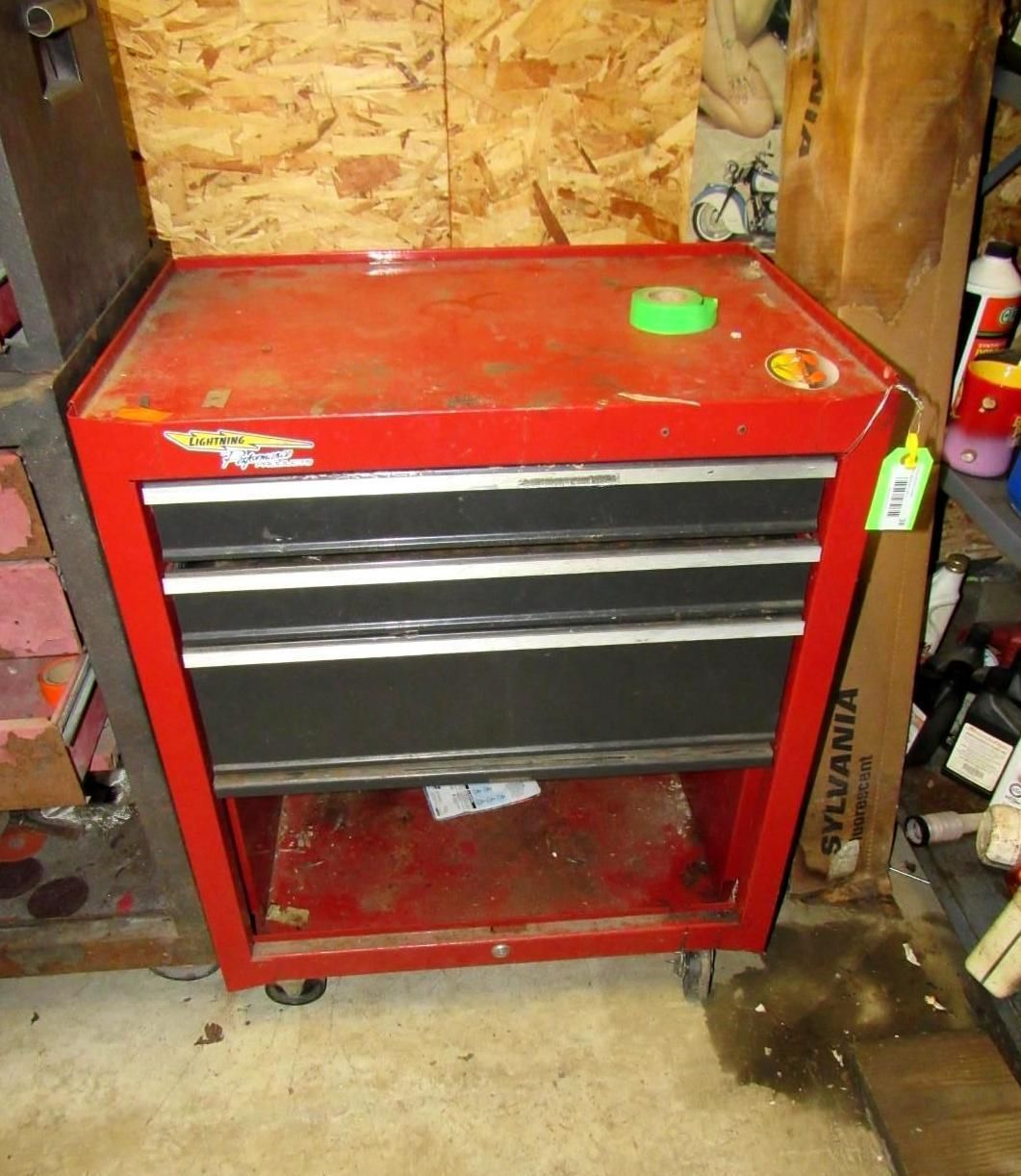 Red and black rolling tool chest in a cluttered workshop.