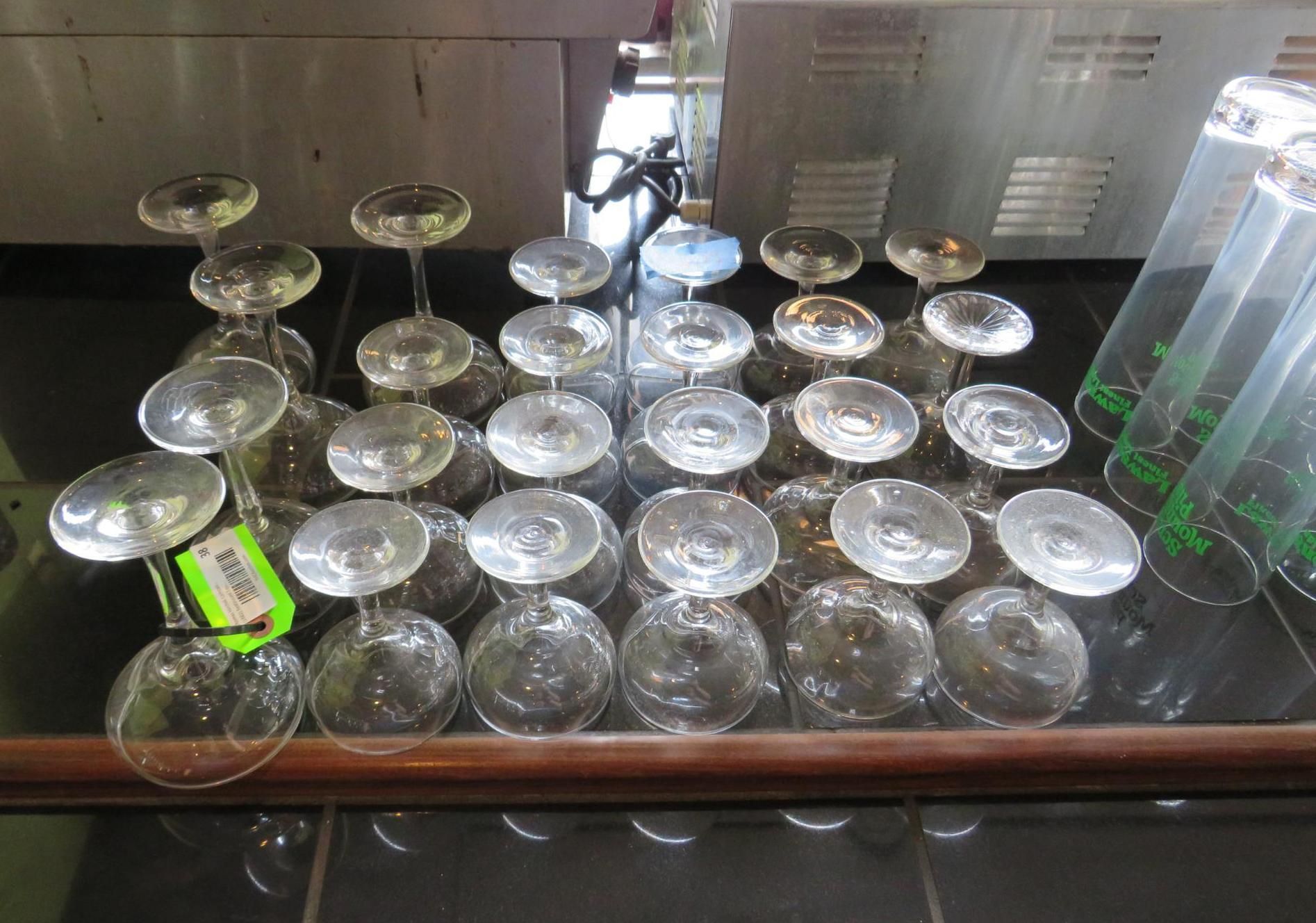 Rows of inverted wine glasses and tall drinking glasses on a counter.