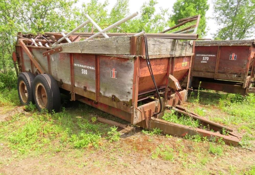Two red International Harvester farm wagons in a grassy field.