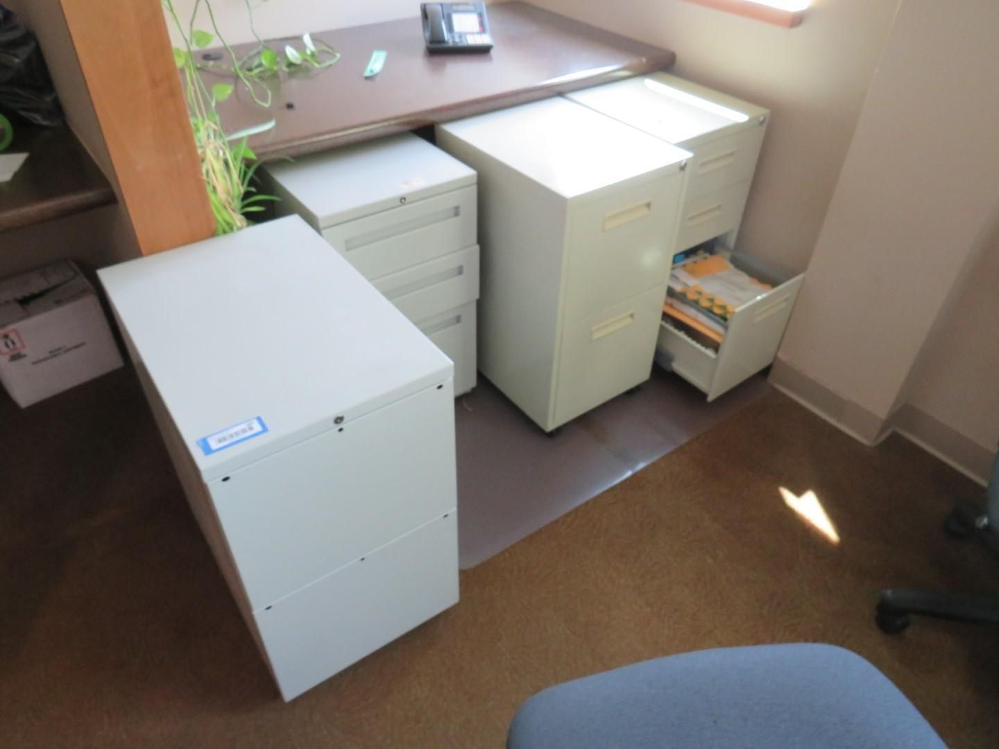 Office area with file cabinets: four white file cabinets under a desk, one drawer open.