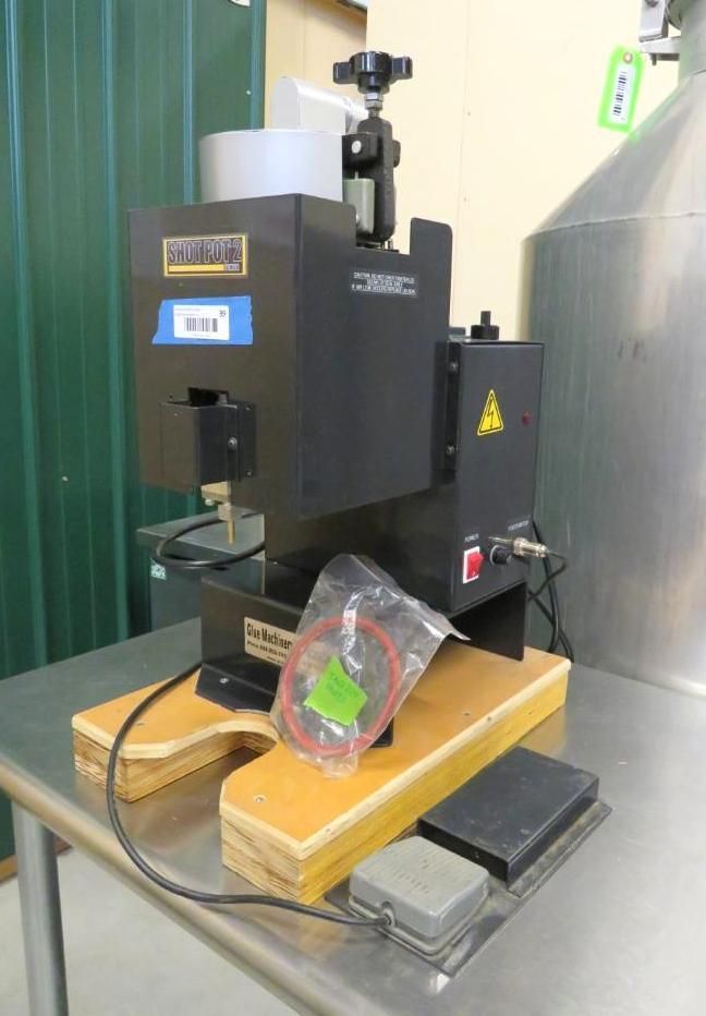 Black industrial machine on a wooden base with a foot pedal.