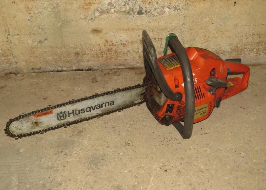 Husqvarna orange chainsaw on a cement floor.