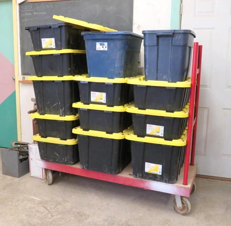 A red cart holds stacks of black and yellow storage bins.