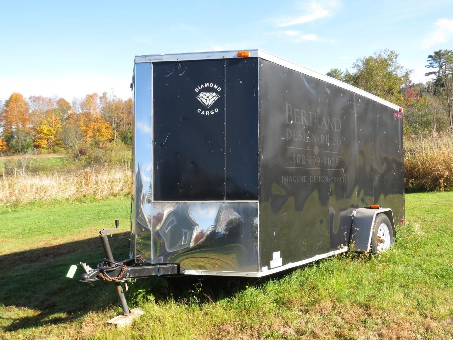 Black enclosed Diamond Cargo trailer parked in a grassy field.