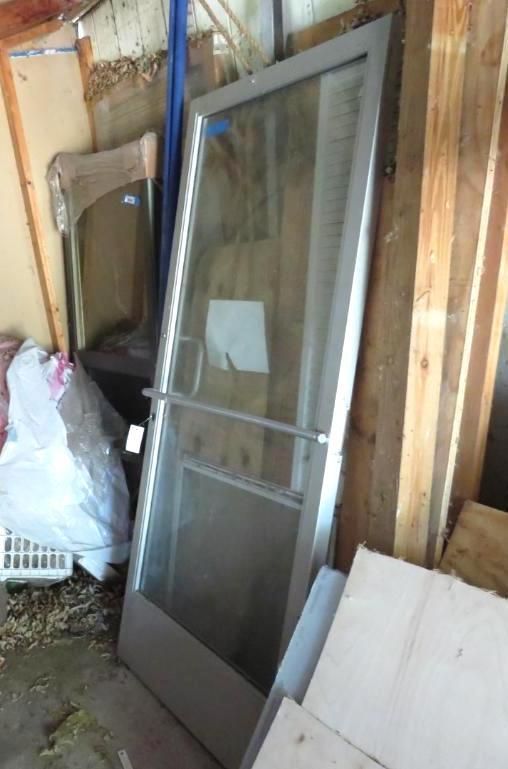 Silver-framed glass door leaning against wooden planks.