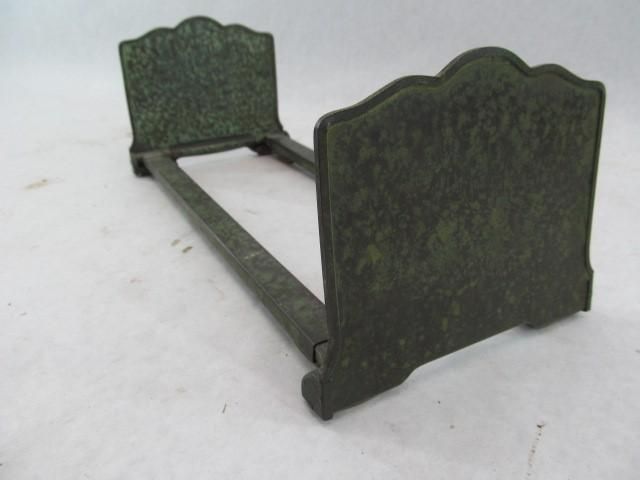 Green metal book holder with ornate, curved edges.