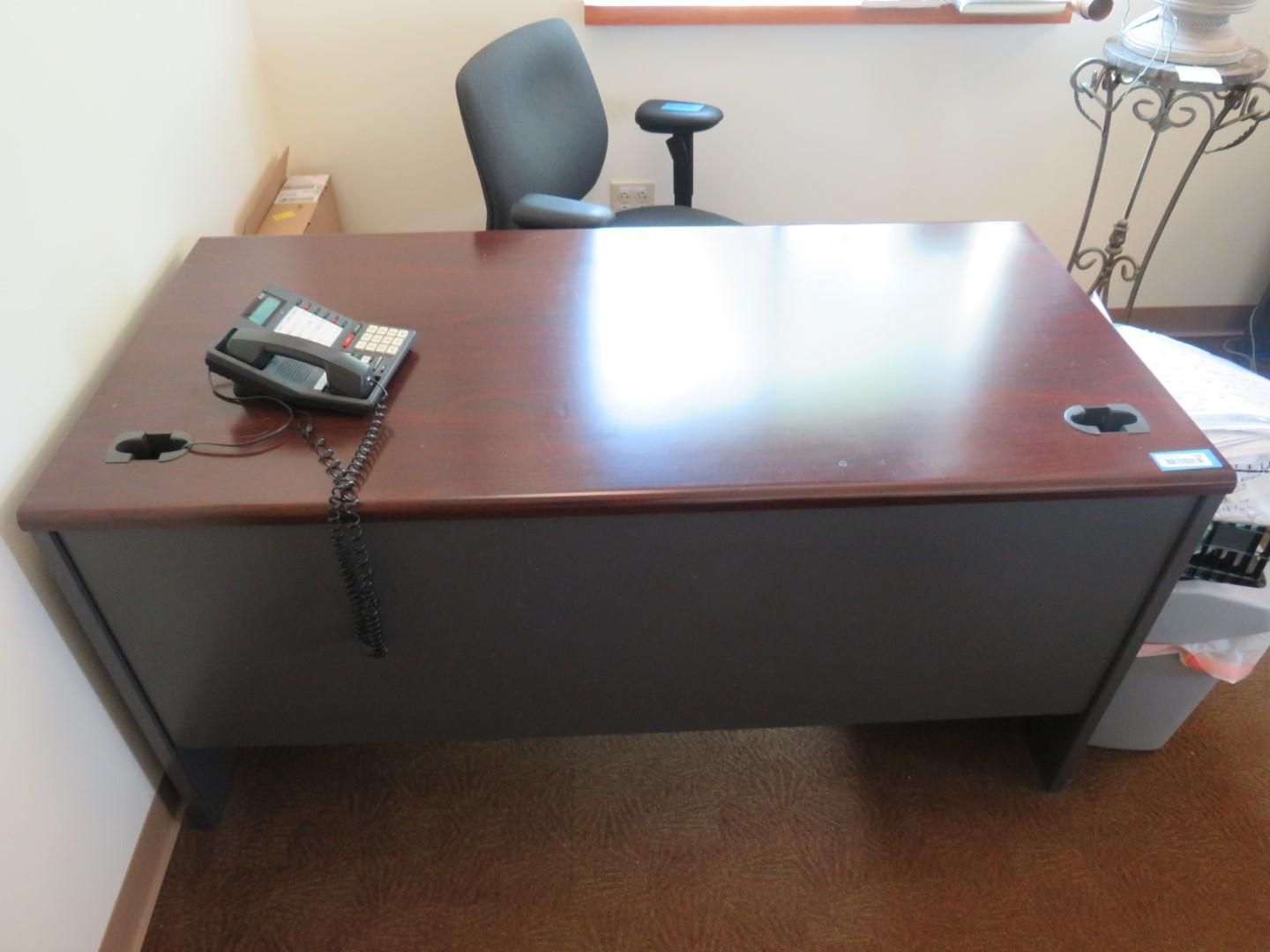 Dark brown office desk with a black phone, black chair in the background, set on brown carpet.