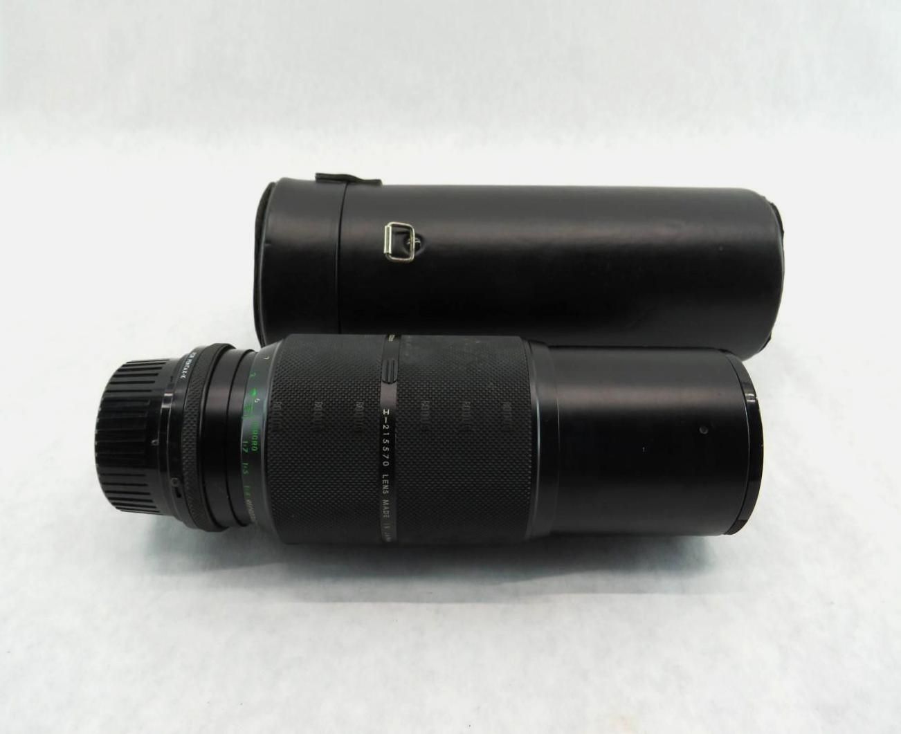 Black camera lens and case on a white surface.