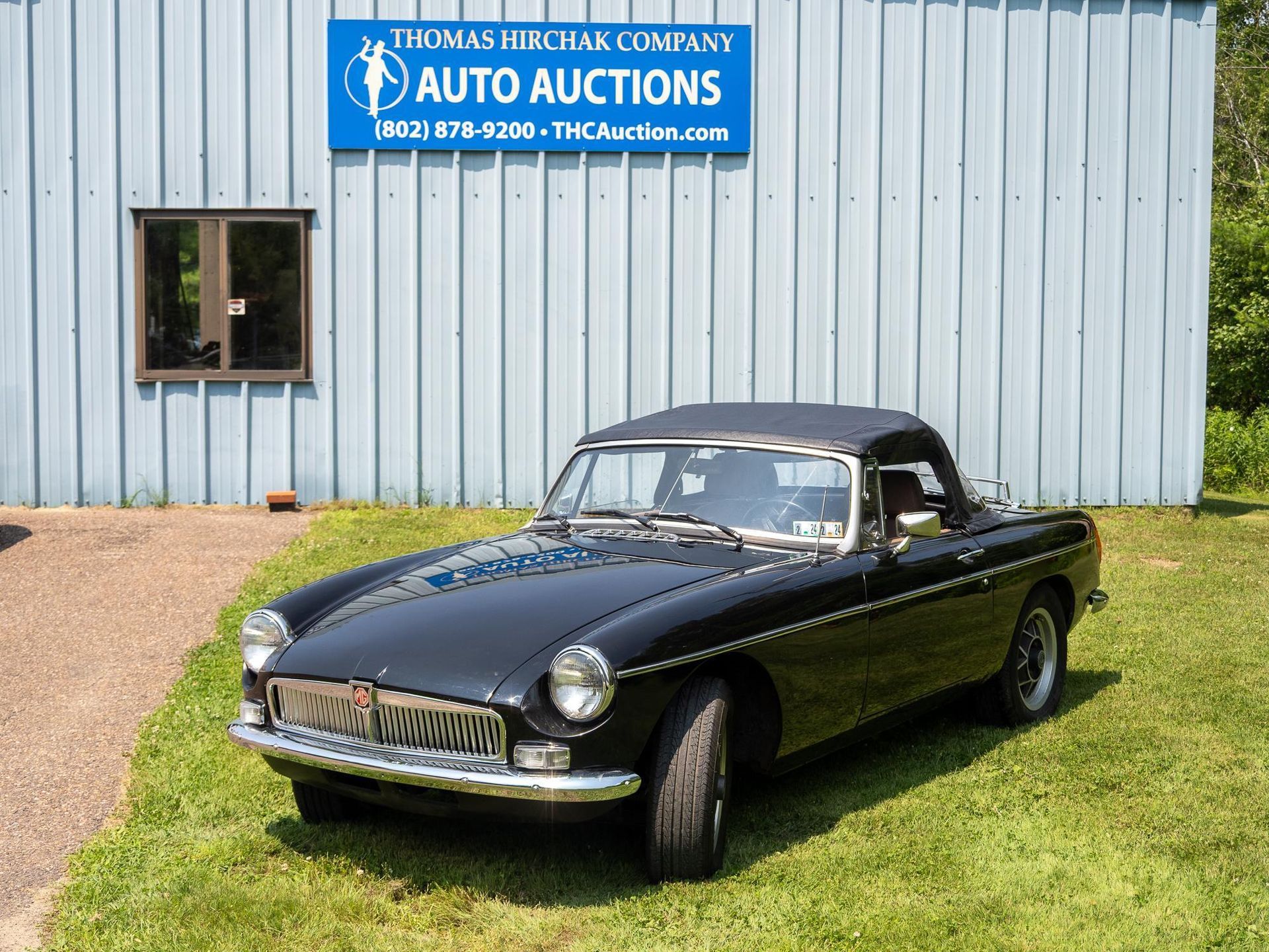 Black convertible car parked in front of an auto auction building.
