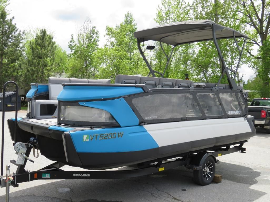 Blue and gray pontoon boat on a trailer, black frame and canopy.