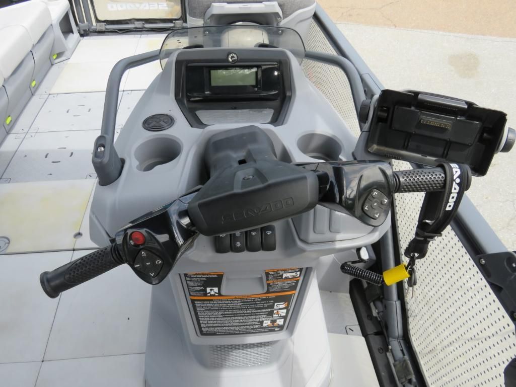 Dashboard of a gray pontoon boat controls with handlebars, cup holders, and a control panel.