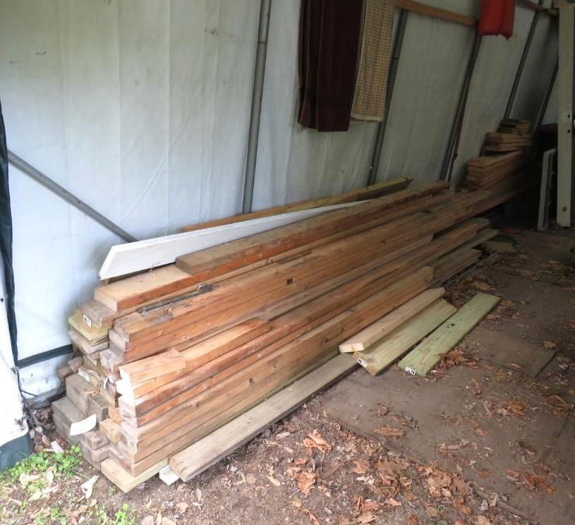Pile of wooden planks inside a white-walled structure.