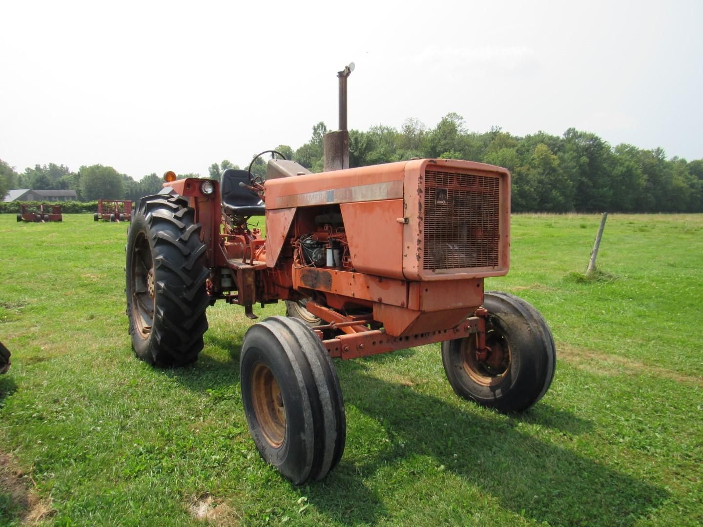 Orange vintage tractor parked in a grassy field.