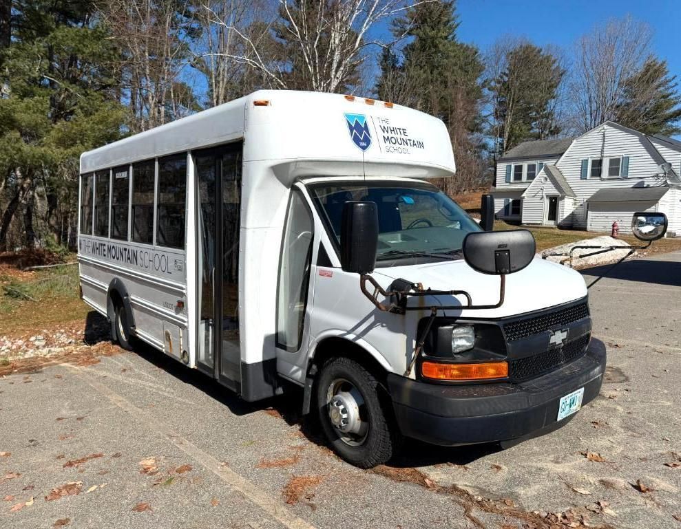 White school bus parked on asphalt, logo above windshield.