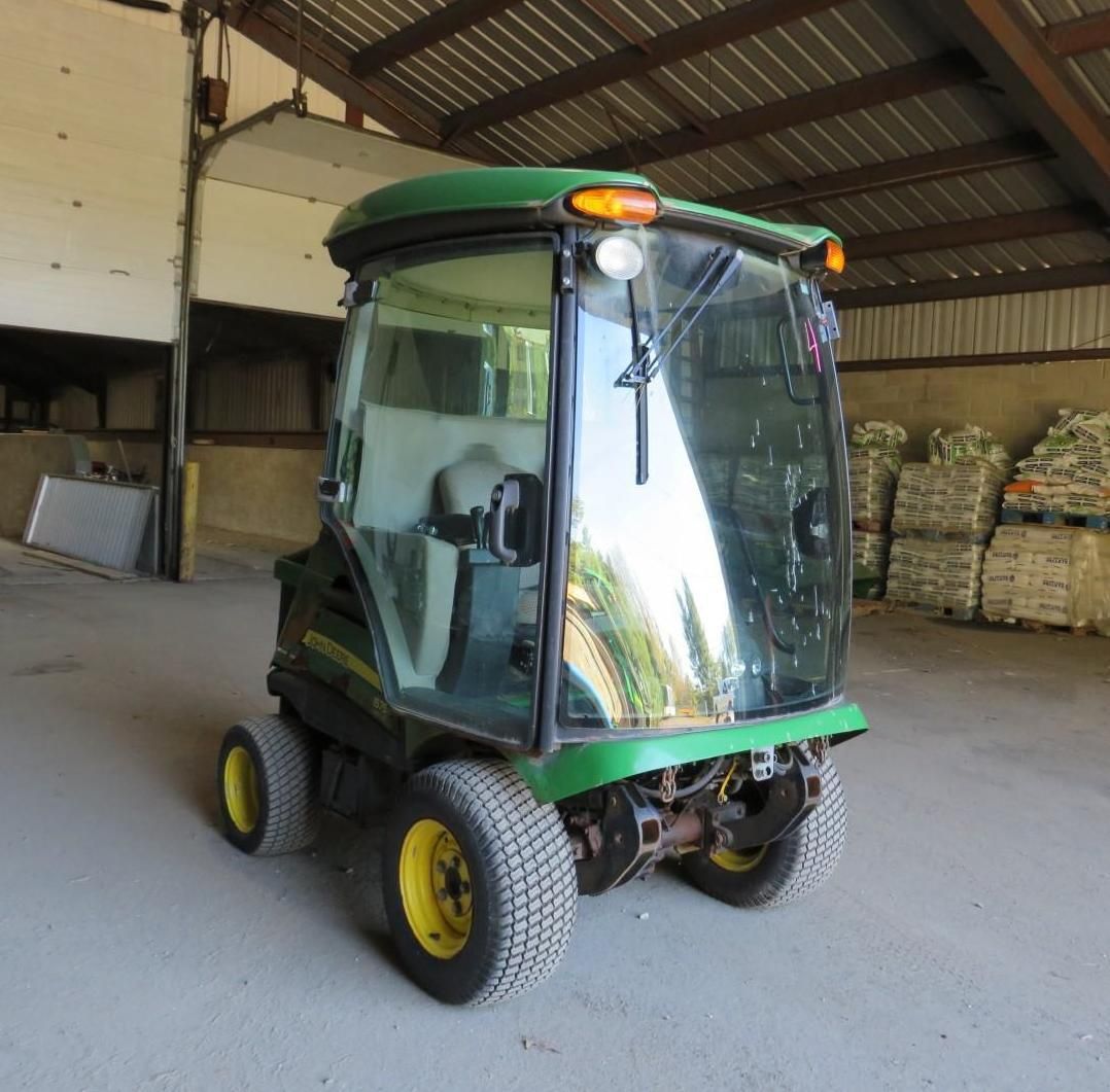 John Deere utility vehicle with a cab, in a shed.