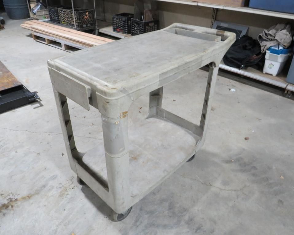 Gray plastic utility cart with wheels in a warehouse.