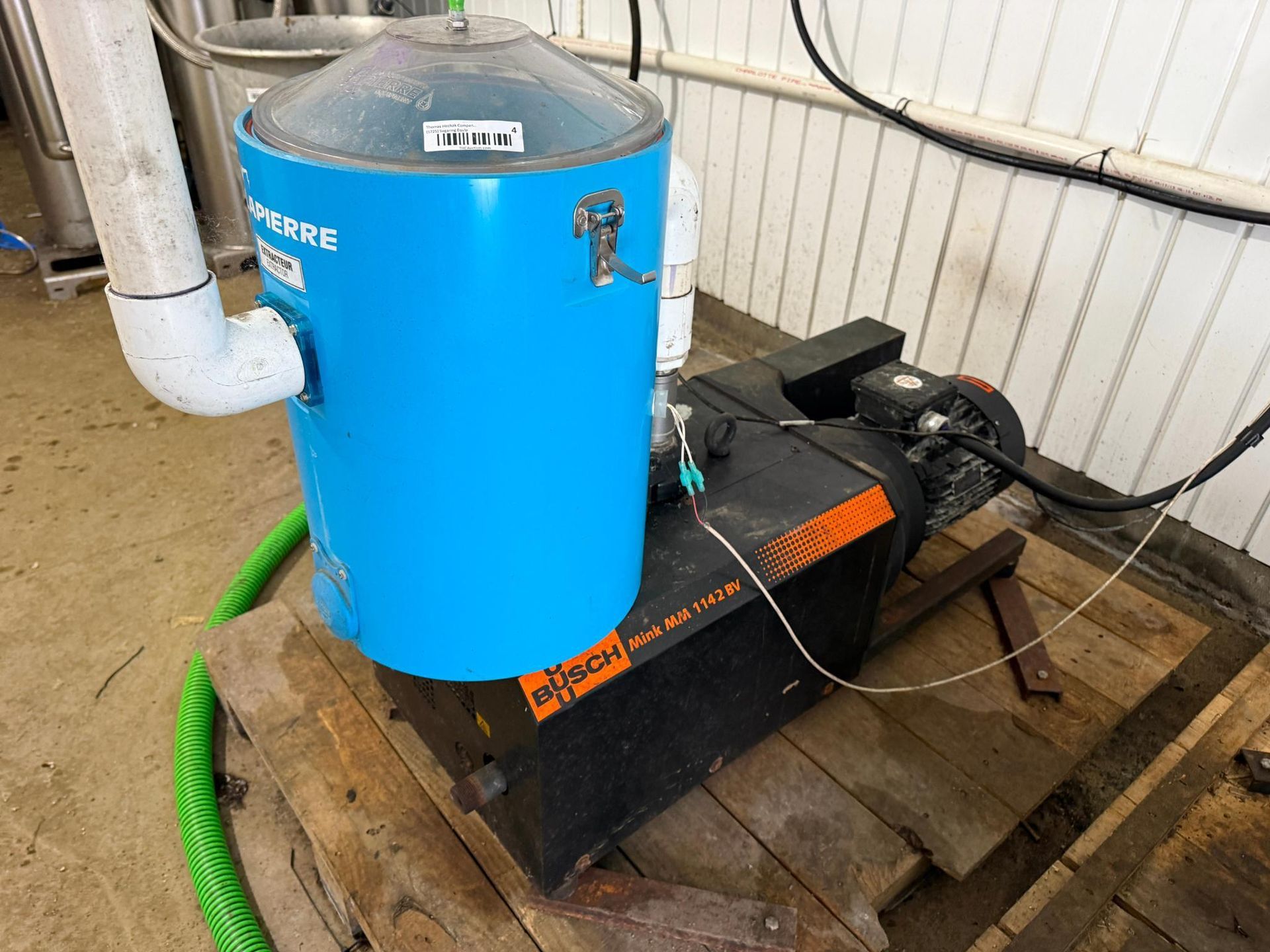 Blue and black industrial equipment on wooden pallet, pipes attached.