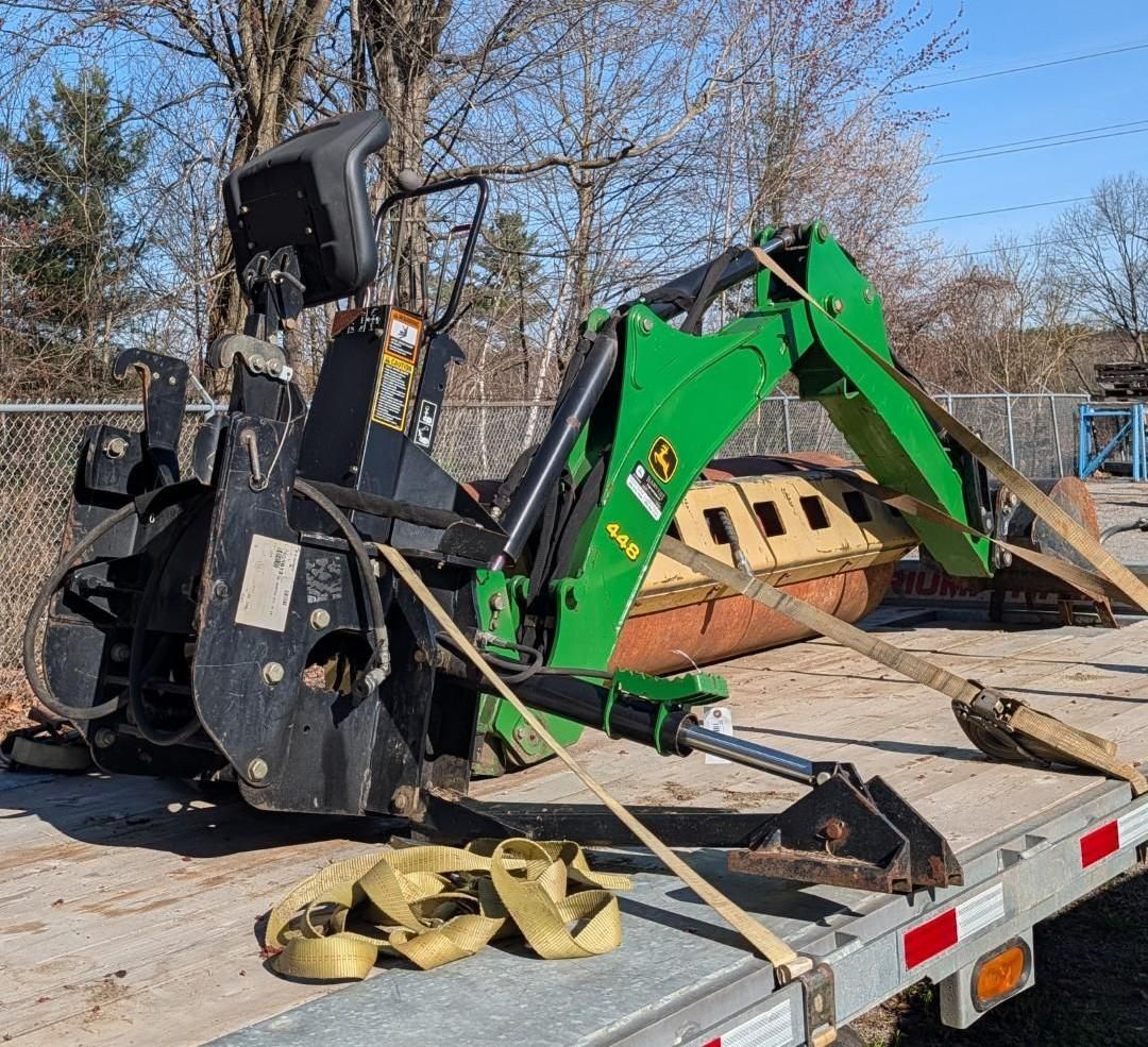 green and black excavator attachments on a flatbed trailer outdoors.